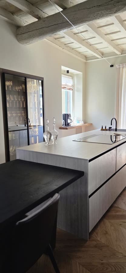 Cucina con isola e vetrata a profili scuri verso il giardino